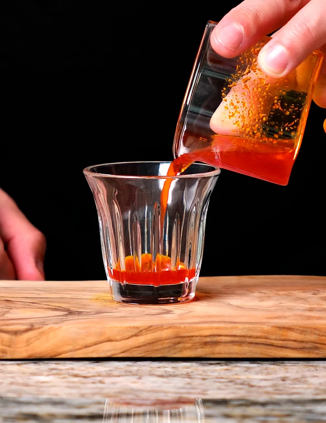 Deep orange saffron extract being poured into a small espresso glass