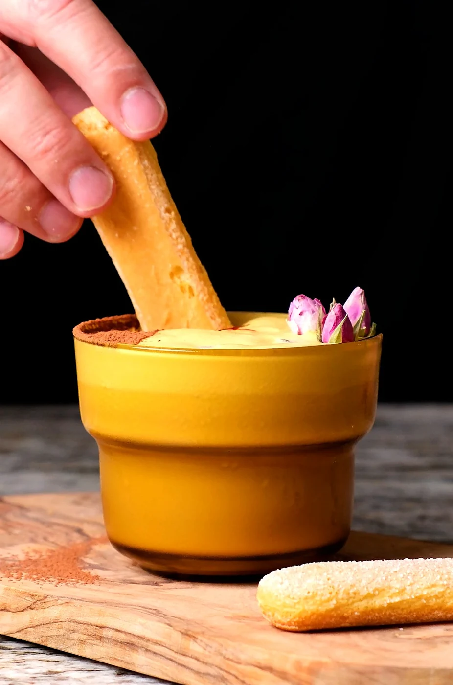 A ladyfinger dipped into a golden Persian Tiramisu drink dusted with cacao